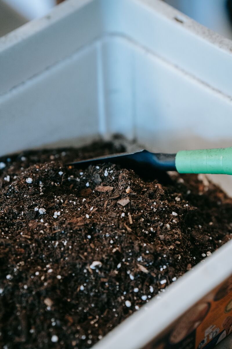 Composteira doméstica de plástico com três camadas aberta mostrando camadas de resíduos orgânicos e terra