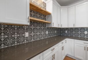 cozinha pequena reformada com armarios pintados de branco azulejo adesivo geometrico puxadores dourados e iluminacao sob armario