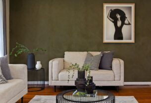 sala de estar com parede de destaque em verde salvia sofa bege e moveis de madeira clara