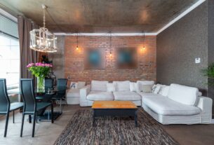 Decoração Estilo Industrial: Como Fazer em Casa Tijolos à vista, canos aparentes, metal enferrujado, madeira crua — quando a decoração estilo industrial surgiu nos anos 1990, muita gente torceu o nariz. Parecia descuido, parecia obra inacabada. Hoje é um dos estilos de decoração mais desejados do mundo — e justamente por isso: porque tem autenticidade. Enquanto outros estilos escondem a estrutura, o industrial a celebra. A decoração estilo industrial nasceu nos lofts de Nova York e Chicago, quando artistas começaram a transformar antigas fábricas e armazéns abandonados em espaços de moradia. O que era limitação virou estética — as vigas expostas, os tijolos sem reboco e os canos à mostra se tornaram os elementos mais valorizados do ambiente. Neste guia, a gente explica como aplicar o estilo industrial na sua casa de forma coerente, sem exageros e sem precisar derrubar paredes ou fazer grandes obras — porque o industrial, quando bem feito, é mais acessível do que parece. O estilo industrial não é sobre imperfeição — é sobre honestidade. Mostrar a estrutura, valorizar o bruto e transformar o funcional em estético. Quando você entende isso, fica fácil aplicar o conceito em qualquer espaço. O Que Define o Estilo Industrial na Decoração Antes de sair comprando móveis de metal e procurar tijolo aparente, é fundamental entender os princípios que definem o estilo industrial. Decoração industrial mal executada vira apenas um ambiente com aparência de reforma inacabada — e a diferença está na coerência. Os pilares do estilo industrial são: Exposição da estrutura: o que normalmente se esconde — tijolos, vigas, canos, dutos — fica à mostra e se torna parte intencional da decoração. Materiais brutos e naturais: concreto, ferro, aço, madeira crua e couro são os materiais protagonistas. Paleta de cores sóbria: cinza, preto, chumbo, marrom, ferrugem e branco sujo dominam — com poucos ou nenhum acento de cor saturada. Imperfeição intencional: superfícies com marcas de uso, patina natural do metal, madeira com veios e nós aparentes — a imperfeição é uma qualidade, não um defeito. Escala generosa: o estilo industrial favorece ambientes com pé-direito alto, janelas grandes e espaços amplos — mas existem adaptações eficientes para espaços menores. Segundo a Faculdade de Arquitetura e Urbanismo da USP, o estilo industrial contemporâneo é uma das correntes mais estudadas no design de interiores brasileiro — especialmente pela forma como dialoga com a realidade das construções urbanas nacionais, que frequentemente têm estrutura aparente por necessidade. A Paleta de Cores do Estilo Industrial A paleta do industrial é sóbria, urbana e deliberadamente afastada dos tons pastéis e vibrantes. Isso não significa ausência de personalidade — significa que a cor vem dos materiais, não da tinta. As Cores Base Cinza: em todas as suas variações — desde o cinza claro do concreto até o grafite escuro do metal. É a cor síntese do industrial. Preto: presente nas estruturas metálicas, nos perfis de janela, nas luminárias e nos detalhes de acabamento. Branco sujo e off-white: nas paredes neutras que servem de fundo para os elementos estruturais mais pesados. Marrom e terracota: vindos da madeira crua e do tijolo — tons quentes que equilibram a frieza do metal e do concreto. As Cores de Acento O estilo industrial admite acentos de cor com moderação — especialmente quando há influência do estilo vintage ou retrô: Ferrugem e cobre — metais oxidados que trazem calor à paleta fria Verde escuro militar — presente em luminárias e objetos decorativos Azul petróleo e denim — acentos sofisticados que complementam o cinza Vermelho tijolo — quando o próprio tijolo aparente já não está presente A sala industrial combina elementos que normalmente ficam escondidos — tijolo, metal, concreto — transformando a estrutura bruta no principal elemento estético do ambiente. Materiais Essenciais do Estilo Industrial Os materiais são o coração do estilo industrial — e a escolha certa deles é o que separa um ambiente autêntico de uma imitação superficial. Tijolo Aparente O tijolo aparente é o elemento mais icônico do estilo industrial. Pode ser aplicado em uma única parede de destaque — o que já transforma completamente o ambiente — ou em todas as paredes para aquele efeito loft total. Como Aplicar Tijolo Aparente Parede de tijolo real: remover o reboco de uma parede existente que tenha tijolo por baixo é a solução mais autêntica e econômica — o tijolo já está lá, só precisa ser revelado. Consulte um engenheiro antes de qualquer intervenção estrutural. Revestimento de tijolinho: placas cerâmicas com textura e aparência de tijolo, aplicadas sobre o reboco existente. Mais prático, sem obra pesada. Veja revestimentos de tijolinho para parede no Amazon. Papel de parede de tijolo: a solução mais acessível e sem obra — perfeita para quem mora de aluguel ou quer testar o estilo sem compromisso. Concreto e Cimento Queimado O concreto aparente e o cimento queimado são os materiais de piso e bancada mais associados ao estilo industrial. O cimento queimado tem a vantagem de poder ser aplicado sobre pisos e paredes existentes — sem necessidade de demolição. A ABNT normatiza a aplicação de cimento queimado e concreto aparente em ambientes internos para garantia de durabilidade e segurança. A aplicação correta exige impermeabilização adequada, especialmente em cozinhas e banheiros. Metal e Ferro Metal é o segundo material mais presente no industrial — aparece nas estruturas, prateleiras, luminárias, puxadores, pernas de móveis e detalhes decorativos. As principais opções: Ferro preto fosco: o mais autêntico ao estilo — presente em estruturas, prateleiras e luminárias. Aço escovado: acabamento mais refinado, frequente em cozinhas industriais. Cobre e bronze: trazem calor à paleta fria do industrial — usados em detalhes e acessórios. Metal enferrujado ou patinado: a oxidação natural do metal é valorizada no estilo — não é descuido, é estética. Madeira Crua e Reaproveitada A madeira no estilo industrial é sempre bruta — com veios, nós e marcas de uso aparentes. Madeira de demolição e reaproveitada é especialmente valorizada por trazer história e autenticidade ao ambiente. Além da estética, o uso de madeira reaproveitada tem apelo sustentável — alinhado com as diretrizes do Ministério do Meio Ambiente sobre consumo sustentável. Madeira certificada pelo FSC Brasil é a alternativa nova que garante origem responsável. Móveis para Decoração Industrial Os móveis do estilo industrial combinam dois materiais principais — madeira e metal — em estruturas simples, robustas e funcionais. O excesso de ornamento é o oposto do industrial. Sala de Estar Industrial Sofá de couro: o couro — natural ou sintético de qualidade — é o revestimento mais associado ao industrial. Tom escuro ou caramelo. Veja sofás de couro estilo industrial no Amazon. Mesa de centro com tampo de madeira e pés de metal: o móvel síntese do industrial — a combinação dos dois materiais principais em um único elemento funcional. Estante de aço e madeira: prateleiras em madeira sustentadas por perfis de aço preto — funcional, estético e de fácil execução. Veja estantes industriais de metal e madeira no Amazon. Poltrona de couro ou lona: modelos com estrutura metálica aparente e estofado em couro ou lona — clássicos do industrial. Cozinha Industrial A cozinha industrial é a aplicação mais natural do estilo — afinal, cozinhas profissionais são o ambiente original do design industrial funcional. Armários com portas de madeira crua ou MDF rústico — sem detalhes ornamentais. Puxadores de cano ou perfil de ferro preto — um detalhe de baixo custo e alto impacto. Bancada de concreto, pedra ou inox — materiais brutos e fáceis de limpar. Prateleiras abertas de madeira e metal — em vez de armários superiores tradicionais. Torneira com acabamento preto fosco ou cobre — o detalhe que completa a estética. A cozinha industrial revela o que as cozinhas tradicionais escondem — bancada de concreto, estrutura metálica e madeira crua criam um ambiente funcional e com muito charme. Iluminação Industrial: Elemento Protagonista No estilo industrial, a luminária não é apenas fonte de luz — é objeto decorativo de protagonismo. É um dos elementos mais fáceis e acessíveis de incorporar ao estilo sem grandes obras. Tipos de Luminária Industrial Pendente de gaiola: o modelo mais icônico do industrial — estrutura metálica em formato de gaiola com lâmpada filamento à vista. Veja pendentes de gaiola industrial no Amazon. Pendente de cone metálico: chapéu de metal esmaltado — clássico das fábricas e armazéns dos anos 1940. Disponível em preto, verde musgo, cobre e grafite. Trilho de spots: trilho de metal com múltiplos spots direcionáveis — muito usado em lofts industriais para iluminação flexível de grandes espaços. Arandela de parede com braço articulado: herança do design industrial de escritórios — funcional e esteticamente coerente com o estilo. Lâmpada filamento à vista: lâmpadas com filamento de tungstênio aparente penduradas em cabos — solução minimalista e de alto impacto visual. Veja lâmpadas de filamento decorativas no Amazon. O Inmetro certifica as lâmpadas quanto à eficiência energética — mesmo as decorativas de filamento têm versões LED que reproduzem a estética com muito menor consumo de energia. Home Office Estilo Industrial O home office industrial é um dos ambientes onde o estilo brilha mais — a estética de trabalho e funcionalidade é completamente coerente com o conceito. Mesa de trabalho: tampo de madeira crua com cavaletes ou pernas de cano — ou tampo de concreto com estrutura metálica. Superfície robusta e com caráter. Prateleiras de metal e madeira: organizações abertas que expõem livros, objetos de trabalho e elementos decorativos — sem portas, sem esconder. Cadeira: couro com estrutura metálica — o clássico das cadeiras de escritório industrial dos anos 1950, hoje muito replicado com excelente resultado. Parede de tijolo ou concreto: o fundo perfeito para o home office industrial — e ainda excelente cenário para videochamadas. Confira nosso guia sobre como organizar home office para combinar a estética industrial com um sistema de organização funcional no dia a dia. O home office industrial combina madeira, metal e tijolo para criar um espaço de trabalho com personalidade forte — funcional, focado e esteticamente coerente. Como Aplicar o Estilo Industrial Sem Obras A boa notícia para quem mora de aluguel ou não quer investir em reforma é que o estilo industrial tem soluções de alto impacto sem nenhuma obra estrutural: Papel de parede de tijolo: reproduz o tijolo aparente sem remover reboco ou aplicar revestimento — removível e sem dano às paredes. Luminárias pendentes industriais: substituir a luminária existente por um pendente industrial é uma das intervenções de maior impacto com menor custo e esforço. Prateleiras de metal e madeira: fáceis de instalar com buchas comuns — não requerem obra e transformam completamente qualquer parede. Móveis e objetos industriais: sofá de couro, mesa com pés de metal, cadeira de estrutura metálica — cada peça incorporada aproxima o ambiente do estilo. Puxadores de metal preto fosco: trocar os puxadores de armários e gavetas por modelos de ferro preto é uma intervenção simples, barata e de grande impacto na cozinha e no banheiro. Plantas em vasos metálicos: cactos, suculentas e samambaia em vasos de metal enferrujado ou galvanizado são acessórios decorativos autênticos do estilo industrial. Veja vasos metálicos industriais no Amazon. Erros Comuns na Decoração Industrial O estilo industrial mal aplicado é facilmente identificável — e evitar esses erros é tão importante quanto conhecer os elementos certos. Exagerar nos materiais brutos: concreto em todos os pisos, tijolos em todas as paredes, metal em todos os móveis — o resultado é um ambiente pesado, frio e sem acolhimento. O industrial precisa de equilíbrio com madeira quente, textêxteis e plantas. Ignorar o conforto: o industrial não é sinônimo de desconforto. Almofadas, tapetes e textêxteis são bem-vindos — desde que nos materiais e cores corretos. Misturar com muitos outros estilos: o industrial combina bem com o rústico, o escandinavo e o minimalista — mas conflita com o provençal, o clássico e o maximalista. A mistura incoerente destrói a identidade do ambiente. Usar metal brilhante: cromado e dourado brilhante são o oposto do industrial — que valoriza o fosco, o oxidado e o envelhecido. Metal brilhante remete ao estilo glamour, não ao industrial. Para uma base sólida de organização que complemente a estética industrial, veja nosso guia de decoração minimalista — os dois estilos compartilham princípios importantes de funcionalidade e curadoria de objetos. Industrial com Toque Brasileiro O estilo industrial brasileiro tem uma identidade própria que o diferencia do loft nova-iorquino original. A mistura do industrial com elementos da cultura e do artesanato nacional cria ambientes únicos: Cerâmica artesanal nordestina em vasos e objetos sobre móveis de metal. Madeira de reflorestamento nacional — eucalipto e pinus tratado — em prateleiras e tampos de mesa. Palha e fibras naturais em luminárias e objetos decorativos — contraste orgânico com o metal. Arte urbana e grafite em painéis ou quadros — a conexão com a cultura industrial das grandes cidades brasileiras. Segundo o Sebrae, o mercado de decoração com artesanato brasileiro cresceu expressivamente — e a combinação de elementos industriais com peças artesanais nacionais é uma tendência consolidada no design de interiores do país. Decoração industrial combina com apartamento pequeno? Sim, com adaptações inteligentes. Em apartamentos pequenos, o estilo industrial funciona melhor quando aplicado em elementos pontuais — luminária pendente industrial, prateleiras de metal e madeira, um espelho com moldura de ferro — sem sobrecarregar o espaço com materiais pesados em excesso. A paleta neutra do industrial (cinza, branco sujo, madeira) favorece a sensação de amplitude em espaços compactos. Quais são os móveis indispensáveis do estilo industrial? Os móveis que mais definem o estilo industrial são: sofá ou poltrona de couro com estrutura metálica, mesa com tampo de madeira crua e pernas de metal, estante ou prateleiras de aço e madeira, e cadeira com estrutura de ferro. Não é necessário ter todos — cada peça incorporada aproxima progressivamente o ambiente do estilo. A luminária pendente industrial é o item isolado de maior impacto por menor custo. É possível fazer decoração industrial sem obras? Totalmente. Papel de parede de tijolo, troca de luminárias, prateleiras de metal e madeira, puxadores de ferro preto fosco e móveis com materiais adequados transformam qualquer ambiente sem uma única obra estrutural. Quem mora de aluguel consegue aplicar o estilo com excelente resultado usando apenas esses recursos reversíveis. Decoração industrial combina com madeira clara? Sim. A madeira clara — pinus natural, eucalipto claro — funciona muito bem no estilo industrial porque cria contraste quente com o metal frio e o concreto cinza. O resultado é um industrial mais acolhedor e menos pesado, frequentemente chamado de industrial escandinavo ou industrial soft. A madeira escura tipo demolição cria um efeito mais bruto e urbano — a escolha depende do resultado desejado. Plantas combinam com decoração industrial? Perfeitamente. As plantas são um dos elementos mais eficientes para humanizar e aquecer o estilo industrial — que, sem elas, pode parecer frio e árido. Espécies rústicas como cactos, suculentas, zamioculca e samambaia em vasos metálicos são os mais coerentes com o estilo. Uma planta de porte médio como figueira lirata ou monstera em vaso de concreto ou metal é o elemento que fecha qualquer composição industrial com excelência. Qual a diferença entre estilo industrial e estilo rústico? Apesar de compartilharem materiais como madeira e pedra, os estilos têm origens e estéticas distintas. O industrial é urbano — nasceu nas fábricas e lofts das cidades — e tem o metal, o concreto e o tijolo como materiais protagonistas. O rústico é rural — remete ao campo, ao interior — e valoriza madeiras maciças, pedras naturais, couro bruto e elementos da natureza sem o metal industrial. A combin