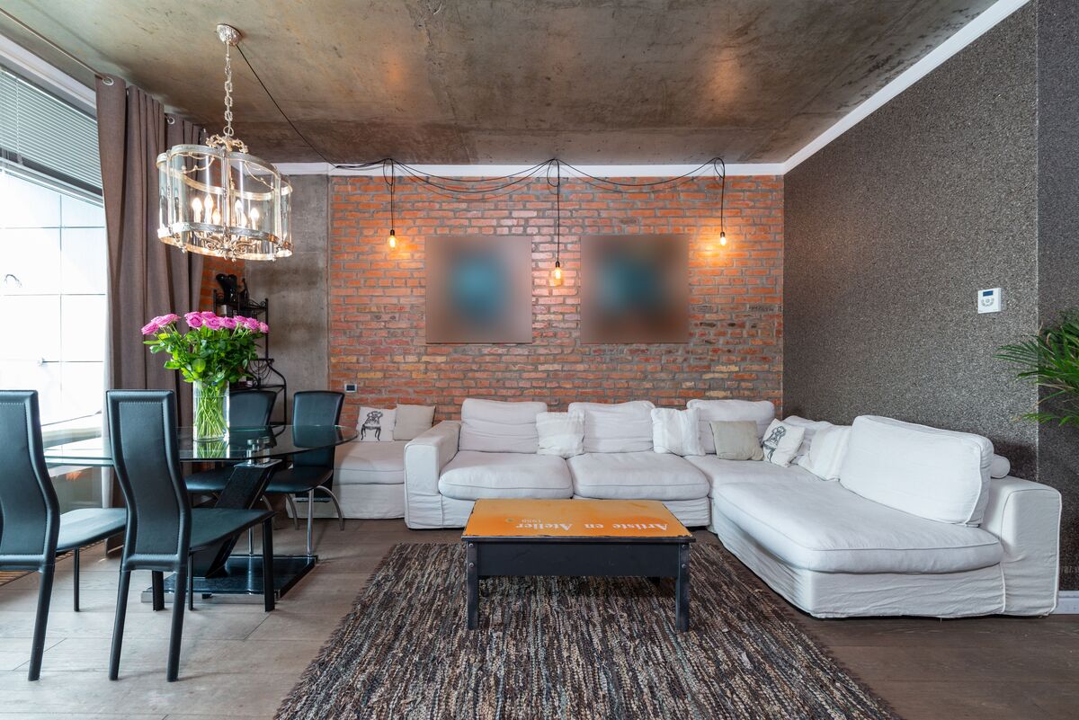 Decoração Estilo Industrial: Como Fazer em Casa Tijolos à vista, canos aparentes, metal enferrujado, madeira crua — quando a decoração estilo industrial surgiu nos anos 1990, muita gente torceu o nariz. Parecia descuido, parecia obra inacabada. Hoje é um dos estilos de decoração mais desejados do mundo — e justamente por isso: porque tem autenticidade. Enquanto outros estilos escondem a estrutura, o industrial a celebra. A decoração estilo industrial nasceu nos lofts de Nova York e Chicago, quando artistas começaram a transformar antigas fábricas e armazéns abandonados em espaços de moradia. O que era limitação virou estética — as vigas expostas, os tijolos sem reboco e os canos à mostra se tornaram os elementos mais valorizados do ambiente. Neste guia, a gente explica como aplicar o estilo industrial na sua casa de forma coerente, sem exageros e sem precisar derrubar paredes ou fazer grandes obras — porque o industrial, quando bem feito, é mais acessível do que parece. O estilo industrial não é sobre imperfeição — é sobre honestidade. Mostrar a estrutura, valorizar o bruto e transformar o funcional em estético. Quando você entende isso, fica fácil aplicar o conceito em qualquer espaço. O Que Define o Estilo Industrial na Decoração Antes de sair comprando móveis de metal e procurar tijolo aparente, é fundamental entender os princípios que definem o estilo industrial. Decoração industrial mal executada vira apenas um ambiente com aparência de reforma inacabada — e a diferença está na coerência. Os pilares do estilo industrial são: Exposição da estrutura: o que normalmente se esconde — tijolos, vigas, canos, dutos — fica à mostra e se torna parte intencional da decoração. Materiais brutos e naturais: concreto, ferro, aço, madeira crua e couro são os materiais protagonistas. Paleta de cores sóbria: cinza, preto, chumbo, marrom, ferrugem e branco sujo dominam — com poucos ou nenhum acento de cor saturada. Imperfeição intencional: superfícies com marcas de uso, patina natural do metal, madeira com veios e nós aparentes — a imperfeição é uma qualidade, não um defeito. Escala generosa: o estilo industrial favorece ambientes com pé-direito alto, janelas grandes e espaços amplos — mas existem adaptações eficientes para espaços menores. Segundo a Faculdade de Arquitetura e Urbanismo da USP, o estilo industrial contemporâneo é uma das correntes mais estudadas no design de interiores brasileiro — especialmente pela forma como dialoga com a realidade das construções urbanas nacionais, que frequentemente têm estrutura aparente por necessidade. A Paleta de Cores do Estilo Industrial A paleta do industrial é sóbria, urbana e deliberadamente afastada dos tons pastéis e vibrantes. Isso não significa ausência de personalidade — significa que a cor vem dos materiais, não da tinta. As Cores Base Cinza: em todas as suas variações — desde o cinza claro do concreto até o grafite escuro do metal. É a cor síntese do industrial. Preto: presente nas estruturas metálicas, nos perfis de janela, nas luminárias e nos detalhes de acabamento. Branco sujo e off-white: nas paredes neutras que servem de fundo para os elementos estruturais mais pesados. Marrom e terracota: vindos da madeira crua e do tijolo — tons quentes que equilibram a frieza do metal e do concreto. As Cores de Acento O estilo industrial admite acentos de cor com moderação — especialmente quando há influência do estilo vintage ou retrô: Ferrugem e cobre — metais oxidados que trazem calor à paleta fria Verde escuro militar — presente em luminárias e objetos decorativos Azul petróleo e denim — acentos sofisticados que complementam o cinza Vermelho tijolo — quando o próprio tijolo aparente já não está presente A sala industrial combina elementos que normalmente ficam escondidos — tijolo, metal, concreto — transformando a estrutura bruta no principal elemento estético do ambiente. Materiais Essenciais do Estilo Industrial Os materiais são o coração do estilo industrial — e a escolha certa deles é o que separa um ambiente autêntico de uma imitação superficial. Tijolo Aparente O tijolo aparente é o elemento mais icônico do estilo industrial. Pode ser aplicado em uma única parede de destaque — o que já transforma completamente o ambiente — ou em todas as paredes para aquele efeito loft total. Como Aplicar Tijolo Aparente Parede de tijolo real: remover o reboco de uma parede existente que tenha tijolo por baixo é a solução mais autêntica e econômica — o tijolo já está lá, só precisa ser revelado. Consulte um engenheiro antes de qualquer intervenção estrutural. Revestimento de tijolinho: placas cerâmicas com textura e aparência de tijolo, aplicadas sobre o reboco existente. Mais prático, sem obra pesada. Veja revestimentos de tijolinho para parede no Amazon. Papel de parede de tijolo: a solução mais acessível e sem obra — perfeita para quem mora de aluguel ou quer testar o estilo sem compromisso. Concreto e Cimento Queimado O concreto aparente e o cimento queimado são os materiais de piso e bancada mais associados ao estilo industrial. O cimento queimado tem a vantagem de poder ser aplicado sobre pisos e paredes existentes — sem necessidade de demolição. A ABNT normatiza a aplicação de cimento queimado e concreto aparente em ambientes internos para garantia de durabilidade e segurança. A aplicação correta exige impermeabilização adequada, especialmente em cozinhas e banheiros. Metal e Ferro Metal é o segundo material mais presente no industrial — aparece nas estruturas, prateleiras, luminárias, puxadores, pernas de móveis e detalhes decorativos. As principais opções: Ferro preto fosco: o mais autêntico ao estilo — presente em estruturas, prateleiras e luminárias. Aço escovado: acabamento mais refinado, frequente em cozinhas industriais. Cobre e bronze: trazem calor à paleta fria do industrial — usados em detalhes e acessórios. Metal enferrujado ou patinado: a oxidação natural do metal é valorizada no estilo — não é descuido, é estética. Madeira Crua e Reaproveitada A madeira no estilo industrial é sempre bruta — com veios, nós e marcas de uso aparentes. Madeira de demolição e reaproveitada é especialmente valorizada por trazer história e autenticidade ao ambiente. Além da estética, o uso de madeira reaproveitada tem apelo sustentável — alinhado com as diretrizes do Ministério do Meio Ambiente sobre consumo sustentável. Madeira certificada pelo FSC Brasil é a alternativa nova que garante origem responsável. Móveis para Decoração Industrial Os móveis do estilo industrial combinam dois materiais principais — madeira e metal — em estruturas simples, robustas e funcionais. O excesso de ornamento é o oposto do industrial. Sala de Estar Industrial Sofá de couro: o couro — natural ou sintético de qualidade — é o revestimento mais associado ao industrial. Tom escuro ou caramelo. Veja sofás de couro estilo industrial no Amazon. Mesa de centro com tampo de madeira e pés de metal: o móvel síntese do industrial — a combinação dos dois materiais principais em um único elemento funcional. Estante de aço e madeira: prateleiras em madeira sustentadas por perfis de aço preto — funcional, estético e de fácil execução. Veja estantes industriais de metal e madeira no Amazon. Poltrona de couro ou lona: modelos com estrutura metálica aparente e estofado em couro ou lona — clássicos do industrial. Cozinha Industrial A cozinha industrial é a aplicação mais natural do estilo — afinal, cozinhas profissionais são o ambiente original do design industrial funcional. Armários com portas de madeira crua ou MDF rústico — sem detalhes ornamentais. Puxadores de cano ou perfil de ferro preto — um detalhe de baixo custo e alto impacto. Bancada de concreto, pedra ou inox — materiais brutos e fáceis de limpar. Prateleiras abertas de madeira e metal — em vez de armários superiores tradicionais. Torneira com acabamento preto fosco ou cobre — o detalhe que completa a estética. A cozinha industrial revela o que as cozinhas tradicionais escondem — bancada de concreto, estrutura metálica e madeira crua criam um ambiente funcional e com muito charme. Iluminação Industrial: Elemento Protagonista No estilo industrial, a luminária não é apenas fonte de luz — é objeto decorativo de protagonismo. É um dos elementos mais fáceis e acessíveis de incorporar ao estilo sem grandes obras. Tipos de Luminária Industrial Pendente de gaiola: o modelo mais icônico do industrial — estrutura metálica em formato de gaiola com lâmpada filamento à vista. Veja pendentes de gaiola industrial no Amazon. Pendente de cone metálico: chapéu de metal esmaltado — clássico das fábricas e armazéns dos anos 1940. Disponível em preto, verde musgo, cobre e grafite. Trilho de spots: trilho de metal com múltiplos spots direcionáveis — muito usado em lofts industriais para iluminação flexível de grandes espaços. Arandela de parede com braço articulado: herança do design industrial de escritórios — funcional e esteticamente coerente com o estilo. Lâmpada filamento à vista: lâmpadas com filamento de tungstênio aparente penduradas em cabos — solução minimalista e de alto impacto visual. Veja lâmpadas de filamento decorativas no Amazon. O Inmetro certifica as lâmpadas quanto à eficiência energética — mesmo as decorativas de filamento têm versões LED que reproduzem a estética com muito menor consumo de energia. Home Office Estilo Industrial O home office industrial é um dos ambientes onde o estilo brilha mais — a estética de trabalho e funcionalidade é completamente coerente com o conceito. Mesa de trabalho: tampo de madeira crua com cavaletes ou pernas de cano — ou tampo de concreto com estrutura metálica. Superfície robusta e com caráter. Prateleiras de metal e madeira: organizações abertas que expõem livros, objetos de trabalho e elementos decorativos — sem portas, sem esconder. Cadeira: couro com estrutura metálica — o clássico das cadeiras de escritório industrial dos anos 1950, hoje muito replicado com excelente resultado. Parede de tijolo ou concreto: o fundo perfeito para o home office industrial — e ainda excelente cenário para videochamadas. Confira nosso guia sobre como organizar home office para combinar a estética industrial com um sistema de organização funcional no dia a dia. O home office industrial combina madeira, metal e tijolo para criar um espaço de trabalho com personalidade forte — funcional, focado e esteticamente coerente. Como Aplicar o Estilo Industrial Sem Obras A boa notícia para quem mora de aluguel ou não quer investir em reforma é que o estilo industrial tem soluções de alto impacto sem nenhuma obra estrutural: Papel de parede de tijolo: reproduz o tijolo aparente sem remover reboco ou aplicar revestimento — removível e sem dano às paredes. Luminárias pendentes industriais: substituir a luminária existente por um pendente industrial é uma das intervenções de maior impacto com menor custo e esforço. Prateleiras de metal e madeira: fáceis de instalar com buchas comuns — não requerem obra e transformam completamente qualquer parede. Móveis e objetos industriais: sofá de couro, mesa com pés de metal, cadeira de estrutura metálica — cada peça incorporada aproxima o ambiente do estilo. Puxadores de metal preto fosco: trocar os puxadores de armários e gavetas por modelos de ferro preto é uma intervenção simples, barata e de grande impacto na cozinha e no banheiro. Plantas em vasos metálicos: cactos, suculentas e samambaia em vasos de metal enferrujado ou galvanizado são acessórios decorativos autênticos do estilo industrial. Veja vasos metálicos industriais no Amazon. Erros Comuns na Decoração Industrial O estilo industrial mal aplicado é facilmente identificável — e evitar esses erros é tão importante quanto conhecer os elementos certos. Exagerar nos materiais brutos: concreto em todos os pisos, tijolos em todas as paredes, metal em todos os móveis — o resultado é um ambiente pesado, frio e sem acolhimento. O industrial precisa de equilíbrio com madeira quente, textêxteis e plantas. Ignorar o conforto: o industrial não é sinônimo de desconforto. Almofadas, tapetes e textêxteis são bem-vindos — desde que nos materiais e cores corretos. Misturar com muitos outros estilos: o industrial combina bem com o rústico, o escandinavo e o minimalista — mas conflita com o provençal, o clássico e o maximalista. A mistura incoerente destrói a identidade do ambiente. Usar metal brilhante: cromado e dourado brilhante são o oposto do industrial — que valoriza o fosco, o oxidado e o envelhecido. Metal brilhante remete ao estilo glamour, não ao industrial. Para uma base sólida de organização que complemente a estética industrial, veja nosso guia de decoração minimalista — os dois estilos compartilham princípios importantes de funcionalidade e curadoria de objetos. Industrial com Toque Brasileiro O estilo industrial brasileiro tem uma identidade própria que o diferencia do loft nova-iorquino original. A mistura do industrial com elementos da cultura e do artesanato nacional cria ambientes únicos: Cerâmica artesanal nordestina em vasos e objetos sobre móveis de metal. Madeira de reflorestamento nacional — eucalipto e pinus tratado — em prateleiras e tampos de mesa. Palha e fibras naturais em luminárias e objetos decorativos — contraste orgânico com o metal. Arte urbana e grafite em painéis ou quadros — a conexão com a cultura industrial das grandes cidades brasileiras. Segundo o Sebrae, o mercado de decoração com artesanato brasileiro cresceu expressivamente — e a combinação de elementos industriais com peças artesanais nacionais é uma tendência consolidada no design de interiores do país. Decoração industrial combina com apartamento pequeno? Sim, com adaptações inteligentes. Em apartamentos pequenos, o estilo industrial funciona melhor quando aplicado em elementos pontuais — luminária pendente industrial, prateleiras de metal e madeira, um espelho com moldura de ferro — sem sobrecarregar o espaço com materiais pesados em excesso. A paleta neutra do industrial (cinza, branco sujo, madeira) favorece a sensação de amplitude em espaços compactos. Quais são os móveis indispensáveis do estilo industrial? Os móveis que mais definem o estilo industrial são: sofá ou poltrona de couro com estrutura metálica, mesa com tampo de madeira crua e pernas de metal, estante ou prateleiras de aço e madeira, e cadeira com estrutura de ferro. Não é necessário ter todos — cada peça incorporada aproxima progressivamente o ambiente do estilo. A luminária pendente industrial é o item isolado de maior impacto por menor custo. É possível fazer decoração industrial sem obras? Totalmente. Papel de parede de tijolo, troca de luminárias, prateleiras de metal e madeira, puxadores de ferro preto fosco e móveis com materiais adequados transformam qualquer ambiente sem uma única obra estrutural. Quem mora de aluguel consegue aplicar o estilo com excelente resultado usando apenas esses recursos reversíveis. Decoração industrial combina com madeira clara? Sim. A madeira clara — pinus natural, eucalipto claro — funciona muito bem no estilo industrial porque cria contraste quente com o metal frio e o concreto cinza. O resultado é um industrial mais acolhedor e menos pesado, frequentemente chamado de industrial escandinavo ou industrial soft. A madeira escura tipo demolição cria um efeito mais bruto e urbano — a escolha depende do resultado desejado. Plantas combinam com decoração industrial? Perfeitamente. As plantas são um dos elementos mais eficientes para humanizar e aquecer o estilo industrial — que, sem elas, pode parecer frio e árido. Espécies rústicas como cactos, suculentas, zamioculca e samambaia em vasos metálicos são os mais coerentes com o estilo. Uma planta de porte médio como figueira lirata ou monstera em vaso de concreto ou metal é o elemento que fecha qualquer composição industrial com excelência. Qual a diferença entre estilo industrial e estilo rústico? Apesar de compartilharem materiais como madeira e pedra, os estilos têm origens e estéticas distintas. O industrial é urbano — nasceu nas fábricas e lofts das cidades — e tem o metal, o concreto e o tijolo como materiais protagonistas. O rústico é rural — remete ao campo, ao interior — e valoriza madeiras maciças, pedras naturais, couro bruto e elementos da natureza sem o metal industrial. A combin