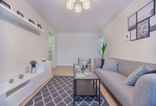 sala de estar minimalista com sofa cinza parede branca e decoracao clean