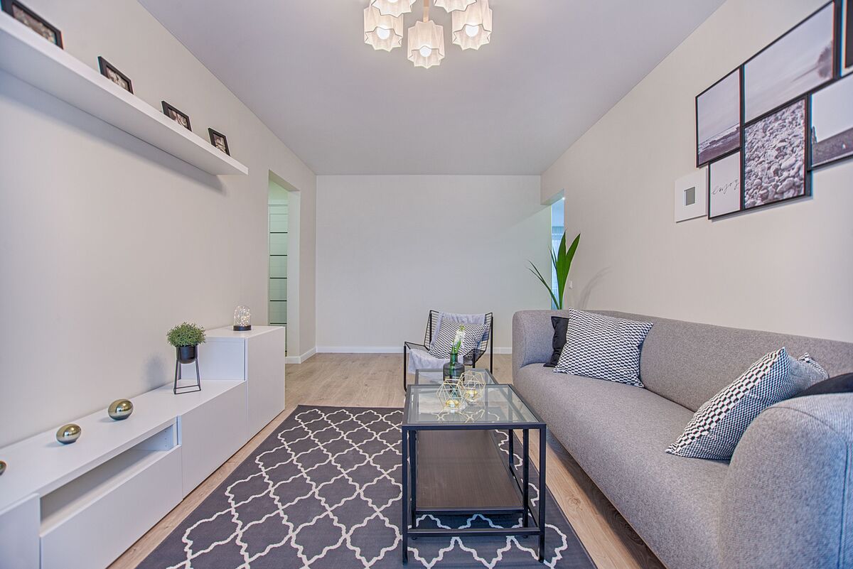 sala de estar minimalista com sofa cinza parede branca e decoracao clean
